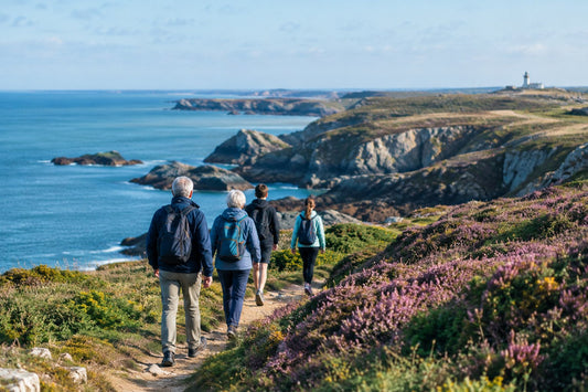 Groupe de marcheurs de tous âges vus de dos sur un sentier côtier de bord de mer atlantique en Bretagne, par une claire matinée d'automne